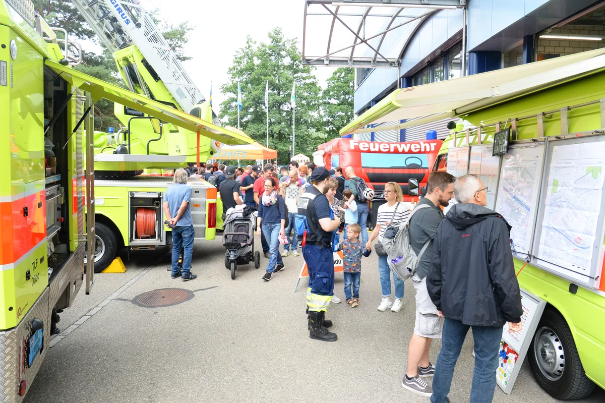 Mehrere Personen begutachten Feuerwehrautos. 